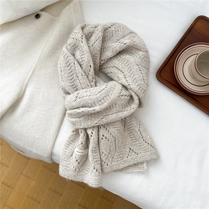 Close-up of beige wool blend scarf featuring delicate knit patterns and brand label