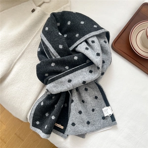 Dettaglio di sciarpa in maglia 100% lana con motivo a pois e trama su tessuto beige