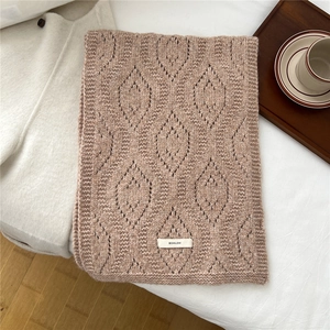 Detailed close-up of hollow knit wool blend scarf in camel color with brand logo label