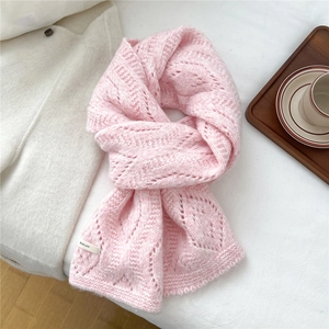 Close-up of the delicate hollow knit texture and brand label on a soft pink wool scarf