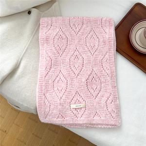 Close-up of pink wool blend knit scarf featuring hollow diamond pattern and logo tag