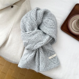 Detail of grey chunky knit wool scarf with hollow diamond pattern and brand label
