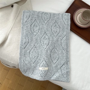 Detail of grey wool blend knit scarf with hollow leaf pattern and ribbed edge detail