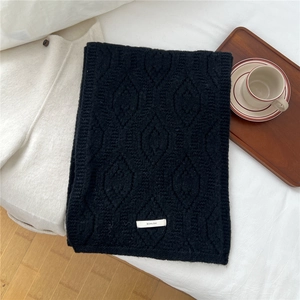 Detail of black wool blend knit scarf with hollow geometric pattern and BOWLOW tag