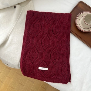Detailed texture of burgundy wool blend knit scarf with classic diamond weave patterns
