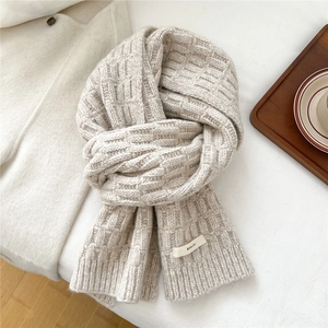 Detailed close-up of beige wool-blend knit scarf with square pattern and ribbed edge