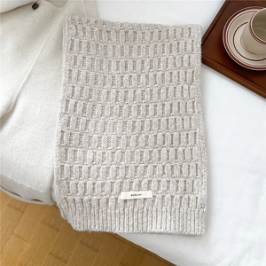 Macro detail of creamy white wool blend knit scarf with textured pattern and brand label
