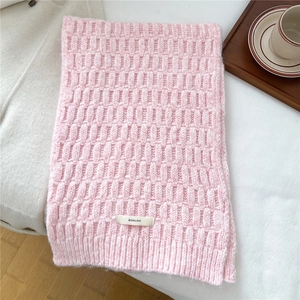 Close-up of pink wool blend scarf showing textured waffle knit pattern and logo label