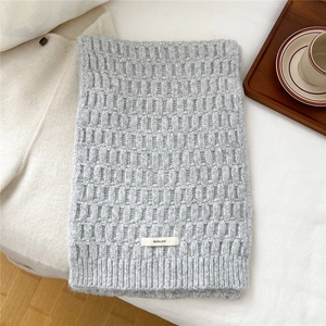 Close-up of a light grey wool blend knit scarf with waffle texture and brand tag