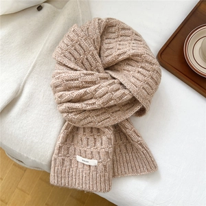 Detailed cable knit texture and brand tag on a cozy beige wool blend winter scarf