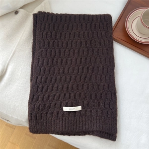 Close-up of dark brown wool blend scarf featuring textured knit pattern and woven brand label