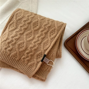 Macro detail of camel wool knit scarf with 100% wool label and cable knit texture