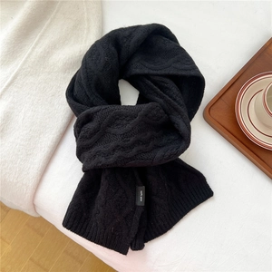Close-up of black wave knit wool scarf with 100% wool label and cable knit texture