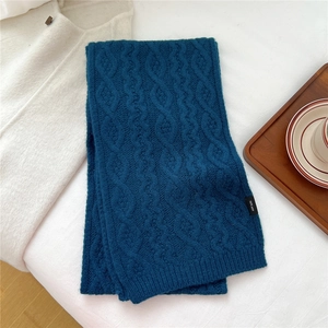 Detail of navy blue cable knit wool scarf with 100% wool label in a cozy setting