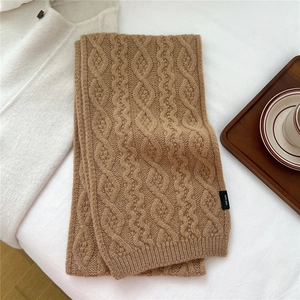 Detailed close-up of camel wave-knit wool scarf texture with 100% wool label display
