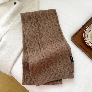 Macro detail of brown chunky knit wool scarf featuring a 100% pure wool washing label