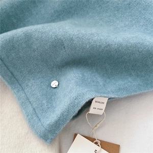 Detail der hellblauen Wollmischung Schal Textur mit Silber Logo und Marken-Waschetikett