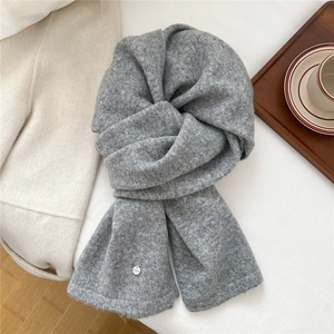 Details des grauen Strickschals mit weicher Wolltextur und silbernem Marken-Emblem