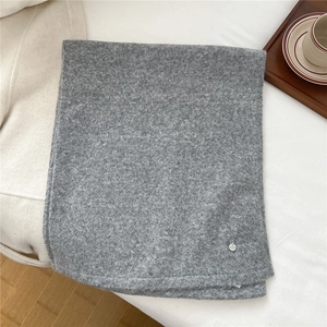 Detailansicht eines grauen Wollschals mit weicher Strickstruktur und metallener Logoschnalle