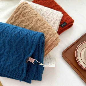 Macro detail of chunky cable knit 100% wool scarves with soft brand tags and quality labels