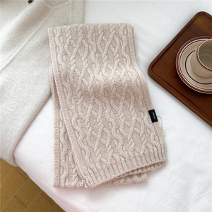 Detail of cable knit wool scarf in cream beige with a 100% wool material label