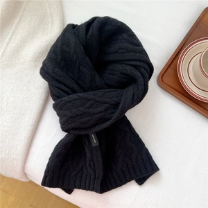 Close-up of chunky cable knit wool scarf texture with 100% wool label in black
