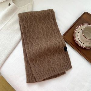 Detail of coffee brown wool scarf showing 100% wool label and cable knit texture