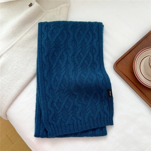 Detail shot of 100% wool label on dark blue cable knit scarf with thick texture