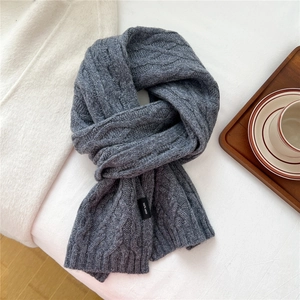 Detailed macro view of dark grey wool scarf with classic cable knit and woven label