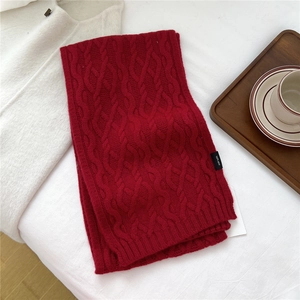 Detail of red cable-knit wool scarf showing intricate 100% wool texture and weave