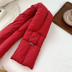 Detail of red quilted puffer scarf featuring a green SUNEY logo tag on a soft texture