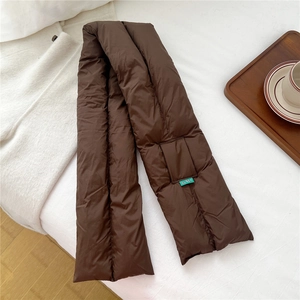 Detailed view of dark brown quilted down scarf with green label on white bedding