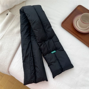 Detail of black quilted down scarf with green SUNEY brand label on white fabric