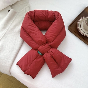 Close-up of red puffer scarf featuring a green logo label and quilted fabric texture