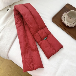 Detail of red quilted down scarf with brand label on a cozy white bed setting