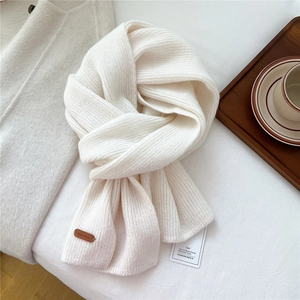 Macro detail of cream knit wool scarf texture with brown leather logo and coffee cup setup