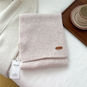 Detailed close-up of knitted wool scarf with leather brand label and texture details