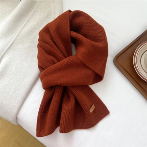 Detail view of caramel knitted wool scarf with textured vertical stripes and leather label
