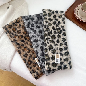 Close-up of soft leopard print plush scarves in three colors with woven labels and warm texture