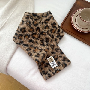 Detail of soft leopard print plush scarf with white square brand tag in home setting