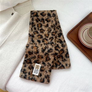 Detail of soft leopard print plush scarf on white fabric next to a coffee cup