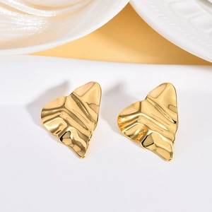 Macro shot of irregular heart-shaped gold studs with wave texture and mirror finish