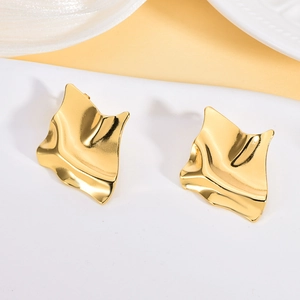 Macro detail of golden irregular geometric stud earrings with embossed wavy texture