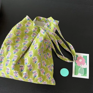 Eco-friendly green floral print cotton canvas tote bag on a black wooden background