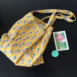 Detail of hand-printed yellow canvas tote bag with floral patterns on black wood