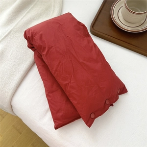 Close-up of red quilted neck warmer with snap buttons on a cozy white background