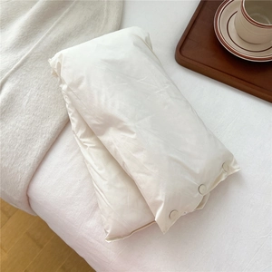 Close-up of white quilted neck warmer featuring three functional side snap buttons