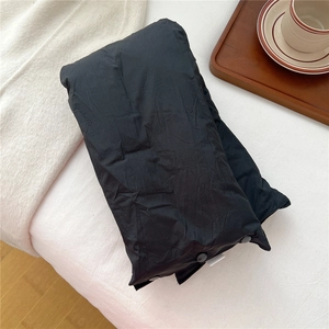Detail of black windproof neck gaiter with snap buttons on minimalist white bedding