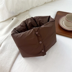 Close-up of a brown quilted neck warmer with button closure on a soft home setting