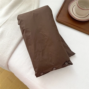 Detail of dark brown puffer scarf with snap button closure on white fabric background